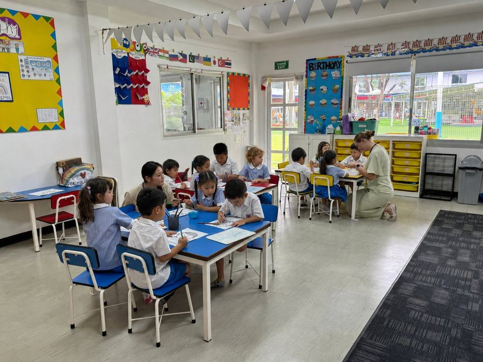 Teachers helping students with a craft activity in a bright, welcoming classroom