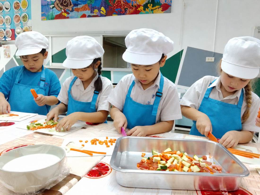 Students in chef hats preparing and chopping vegetables together during Cooking Club
