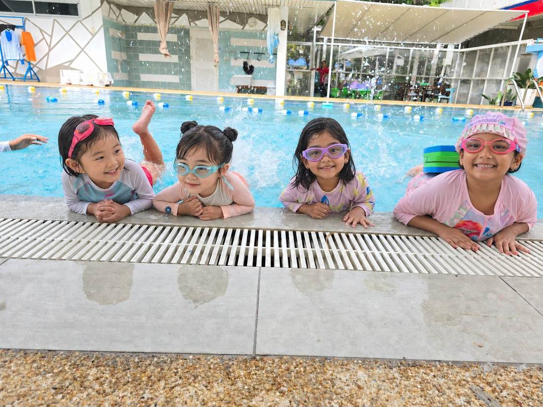 Students smiling together at the pool edge during Swimming Club